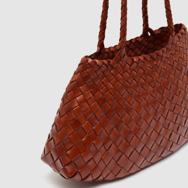 Close-up view of brown woven leather tote bag highlighting intricate texture and craftsmanship.