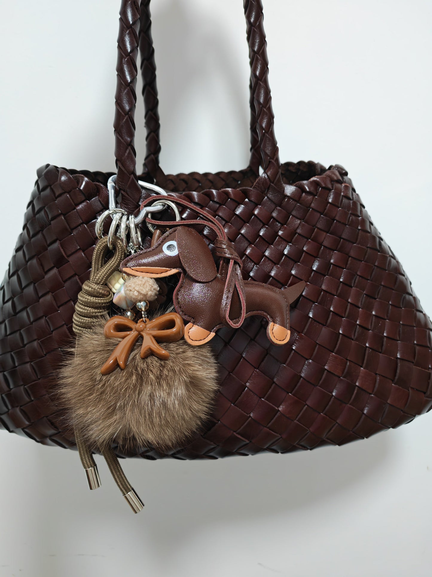 Kiki Luxe Charm bag accessory on brown woven bag.
