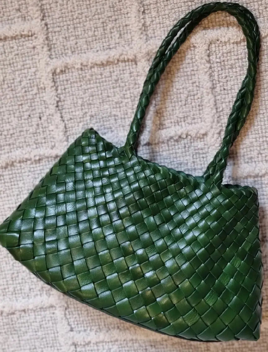 Green woven handbag on a textured beige surface