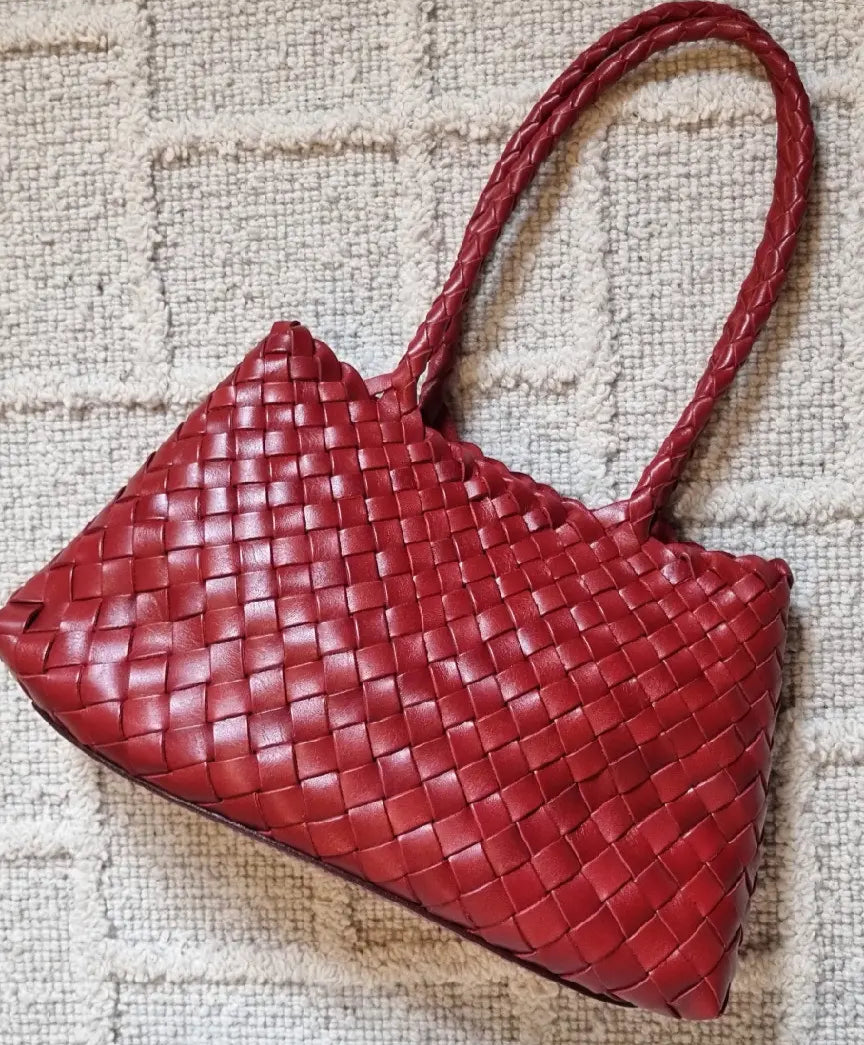 Red woven handbag on a textured beige surface