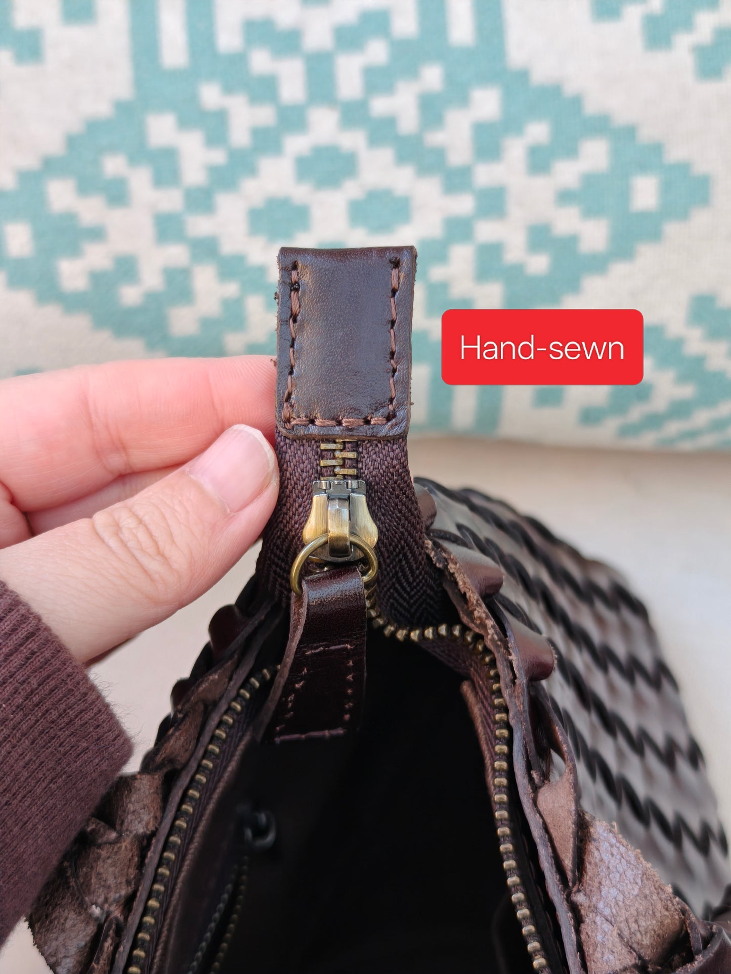 Close-up of a hand-sewn leather zipper on a bag