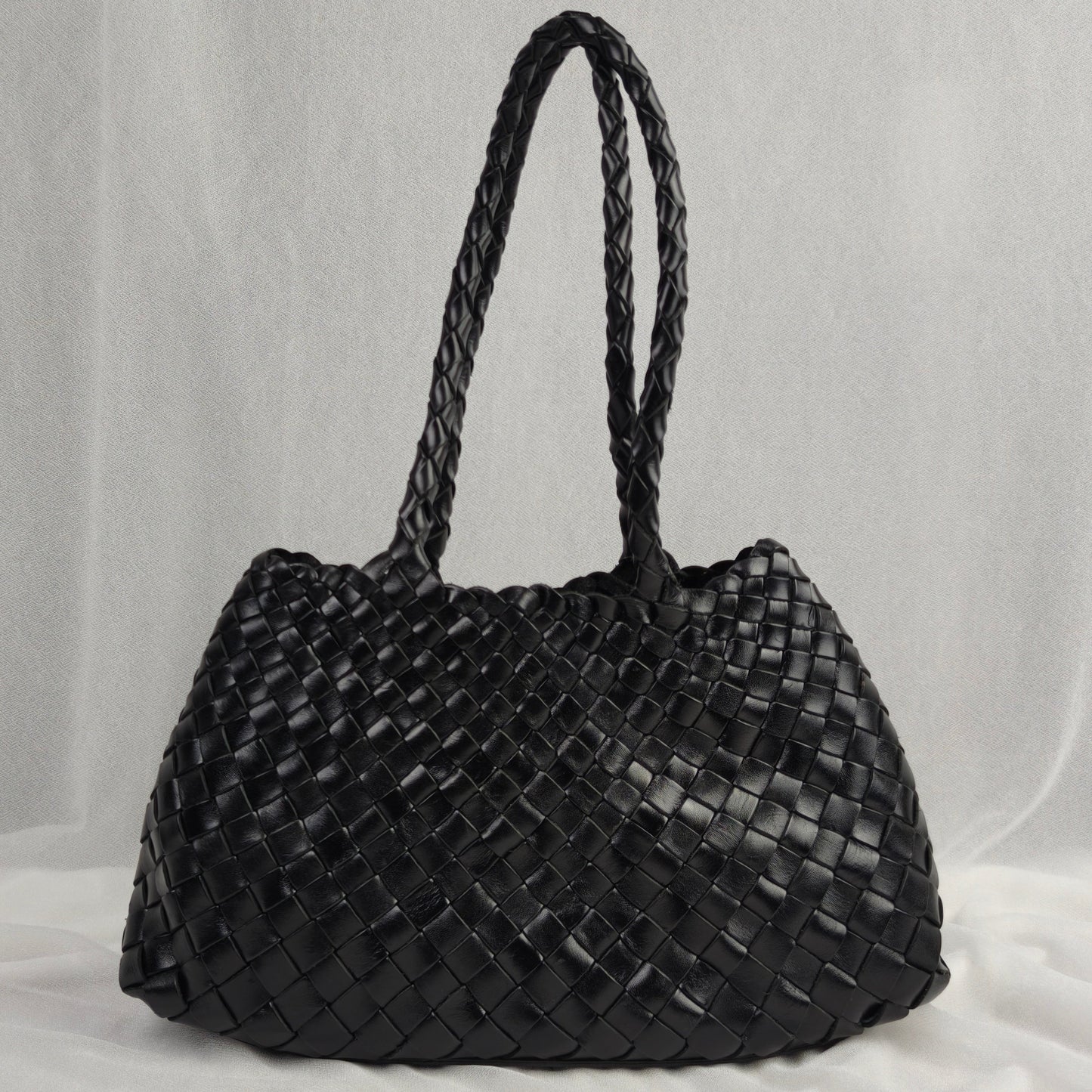 Black woven handbag on a light gray background