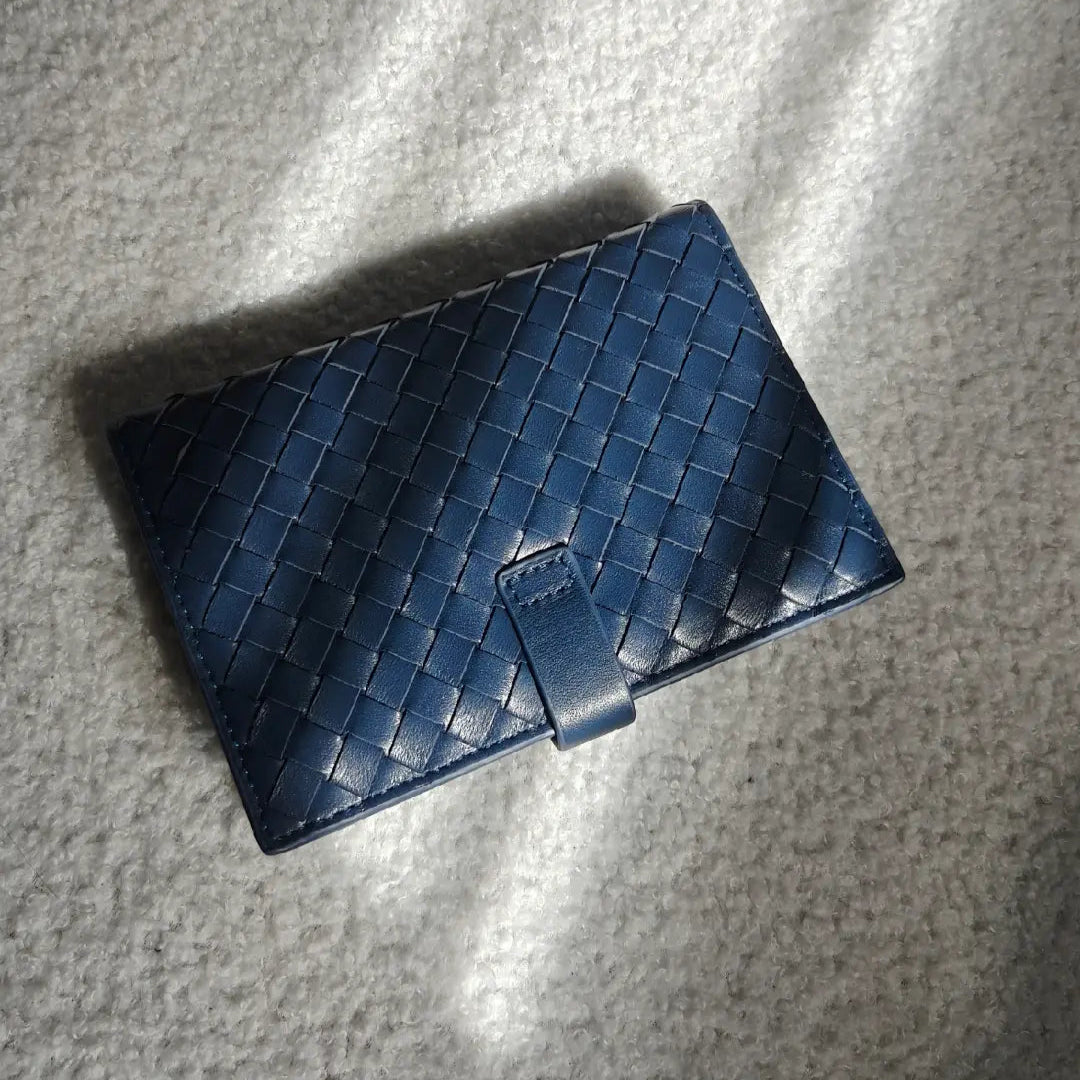back of a blue woven leather passport holder on a textured gray surface