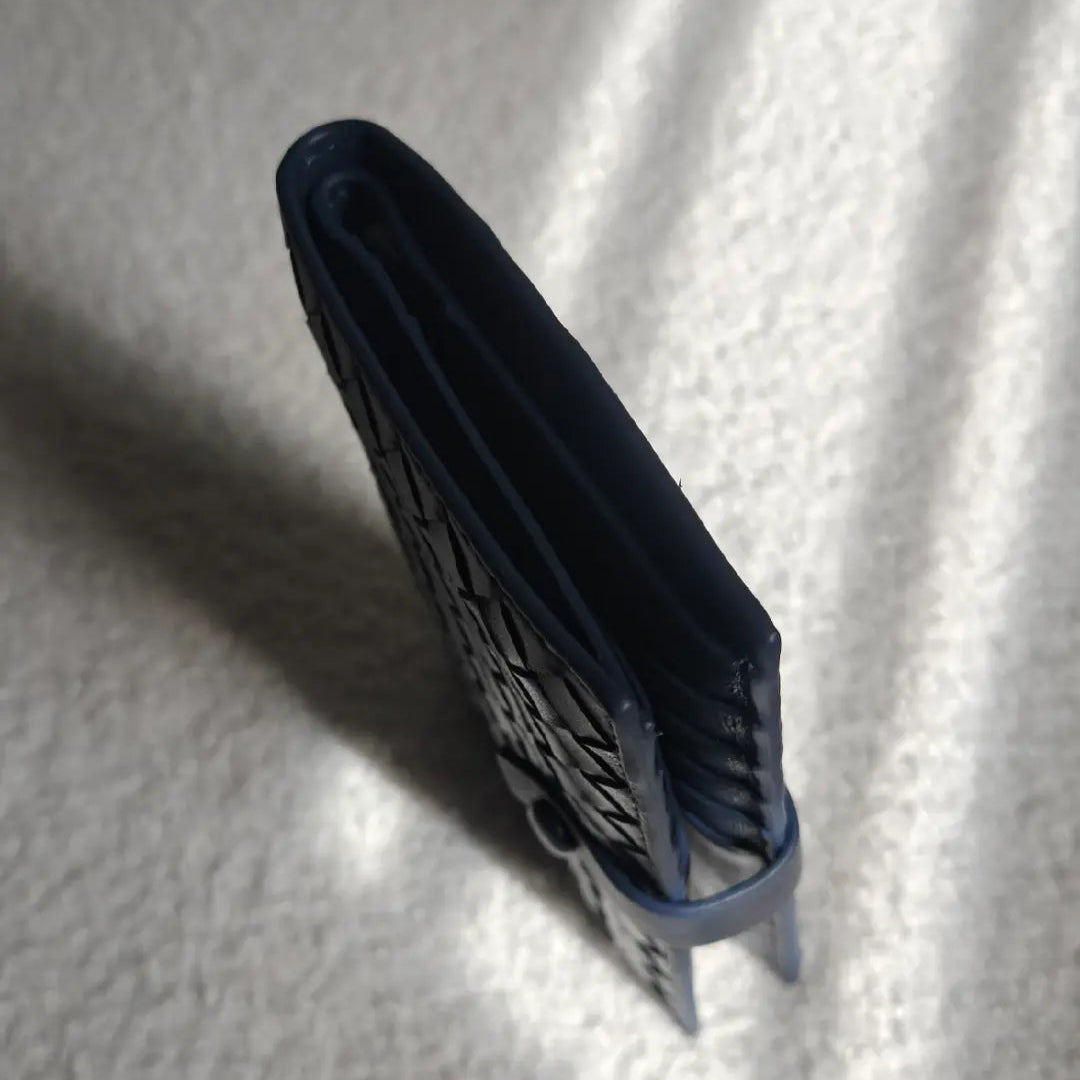 Navy passport holder standing up on a textured white surface