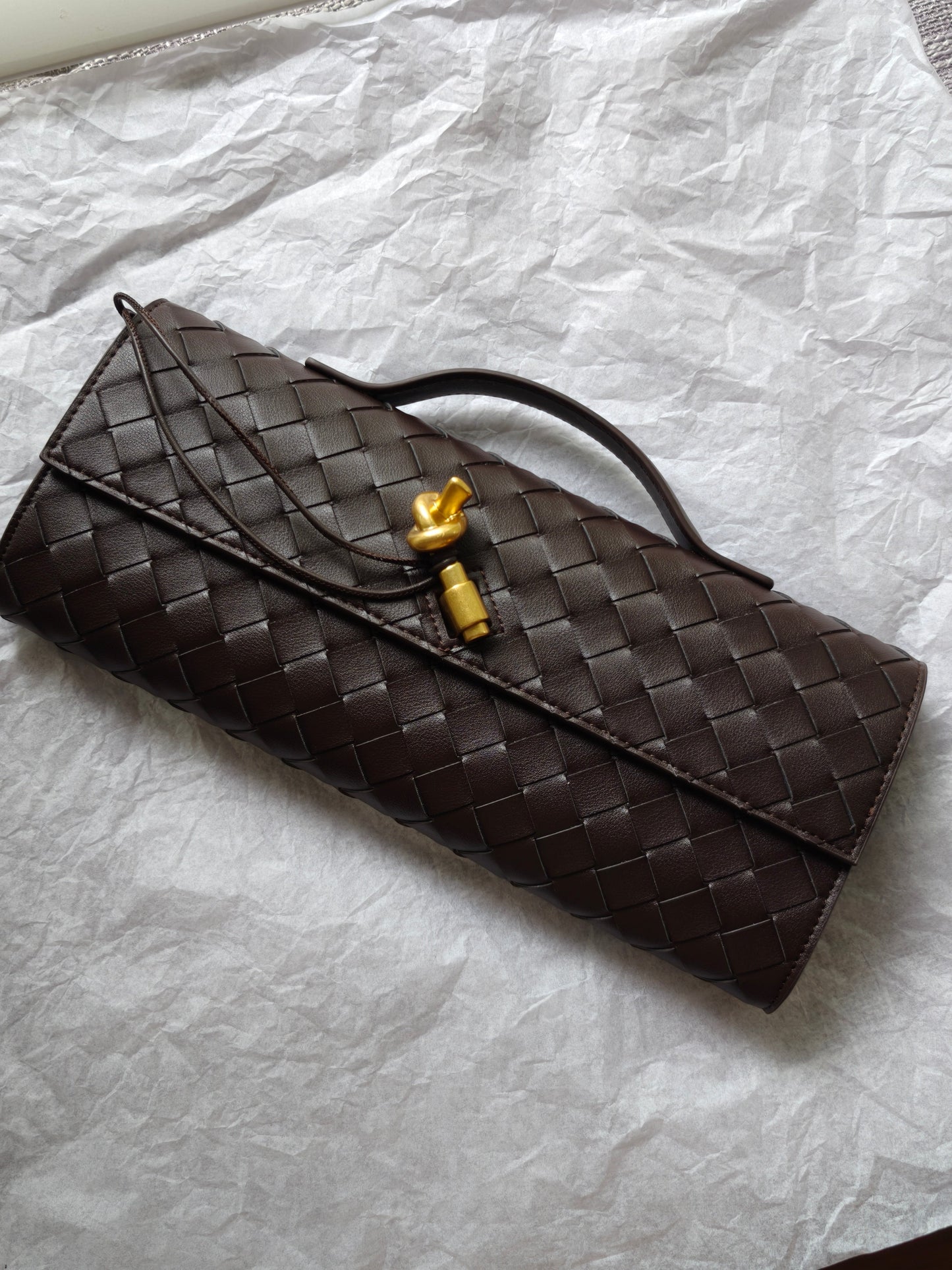 Kiva woven leather baguette bag with pin lock closure, full-grain leather, sleek silhouette, top handle design, brown.