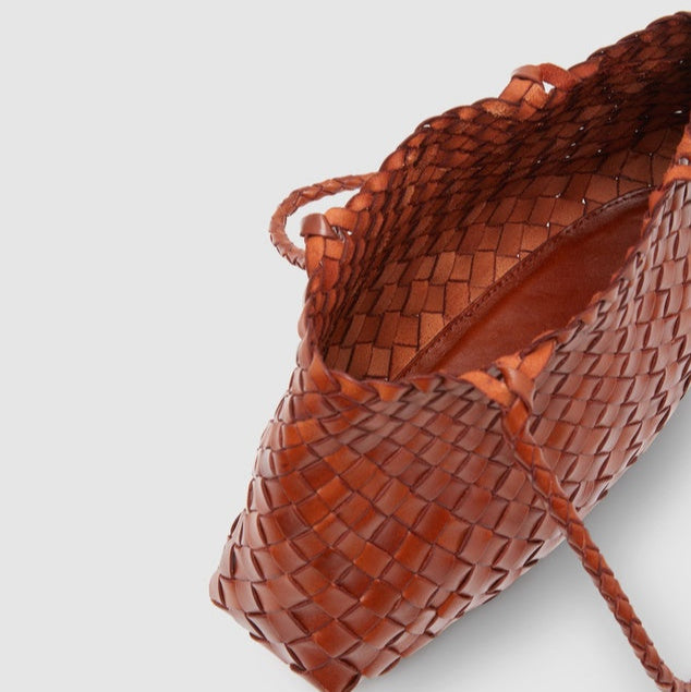 Top view of tan leather woven tote bag with open interior, showcasing spacious unlined design and braided handles.