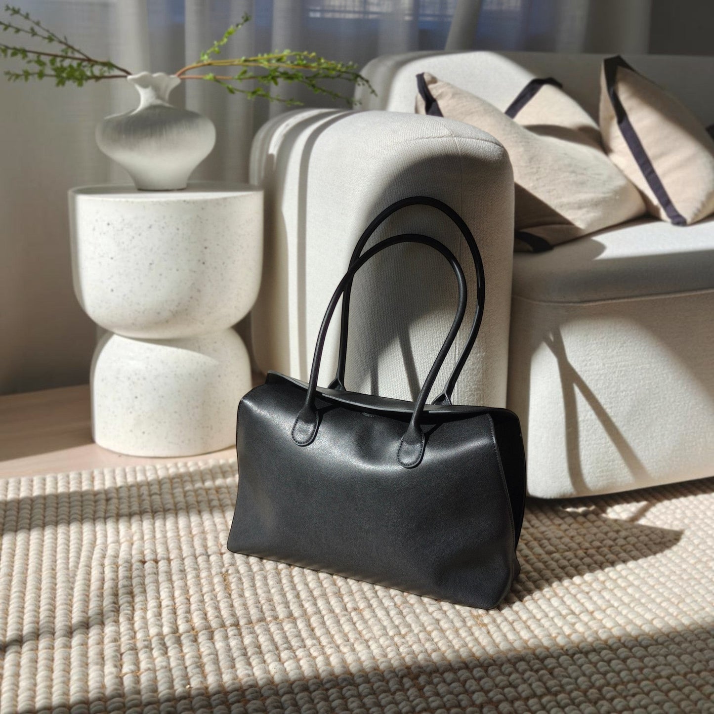 Black valentina leather handbag on a textured surface with a neutral background