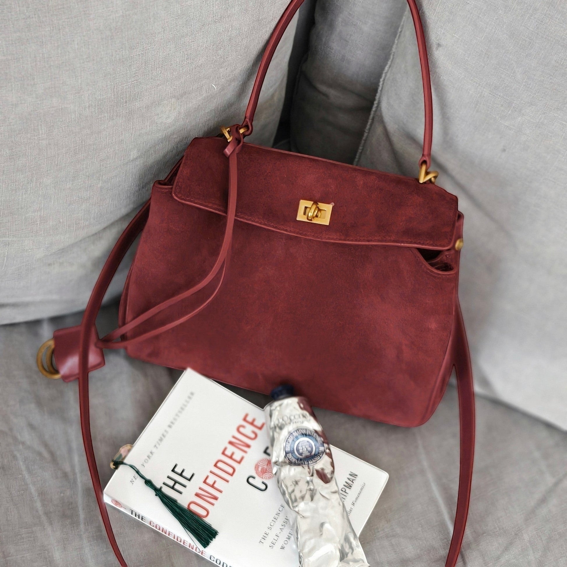 Red handbag on a gray surface with a book underneath