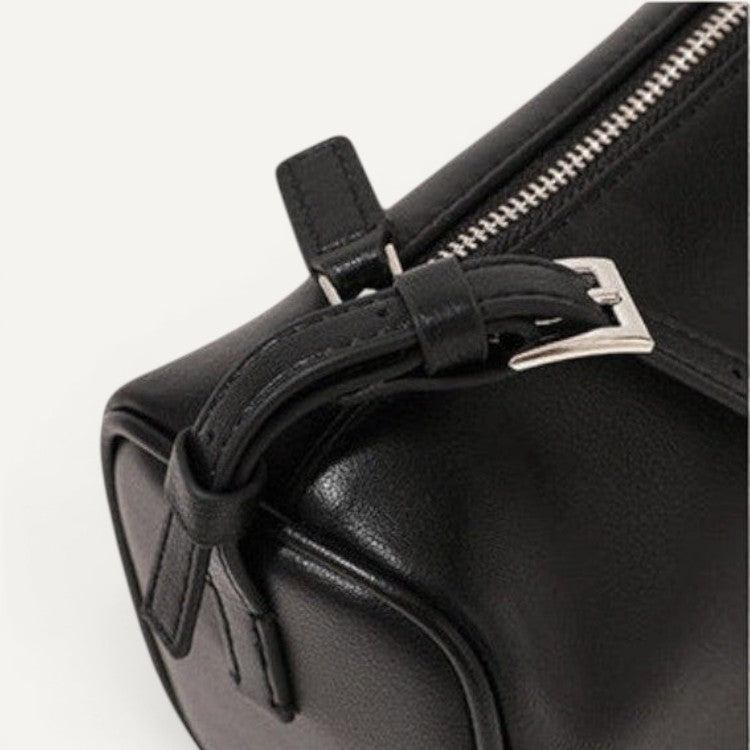 Close-up of a black handbag with a silver buckle on a white background