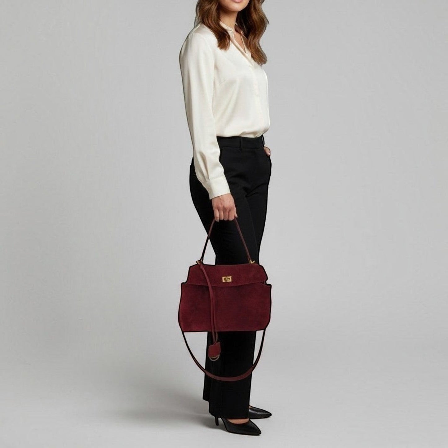 Woman holding a Harper small size maroon handbag against a plain background