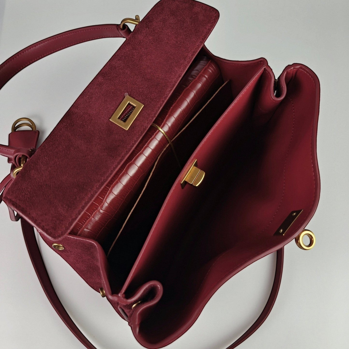 burgundy harper handbag with gold accents on a light gray background