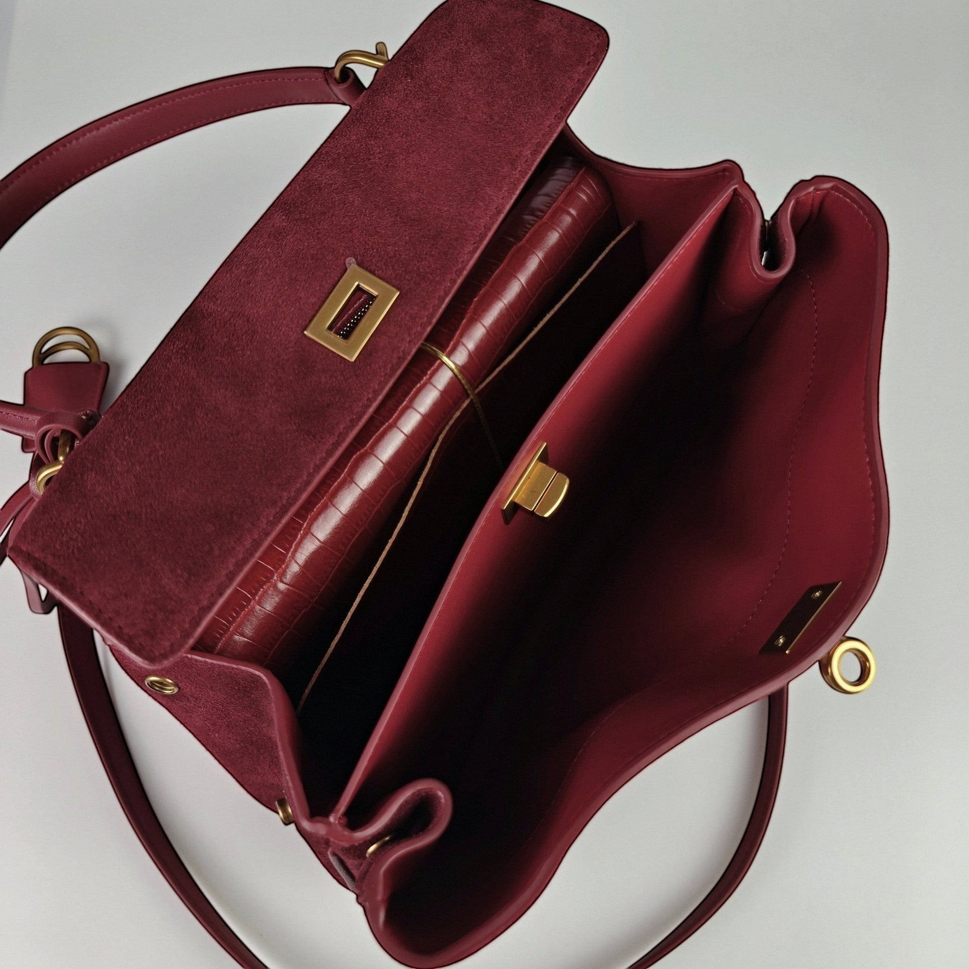 burgundy harper handbag with gold accents on a light gray background