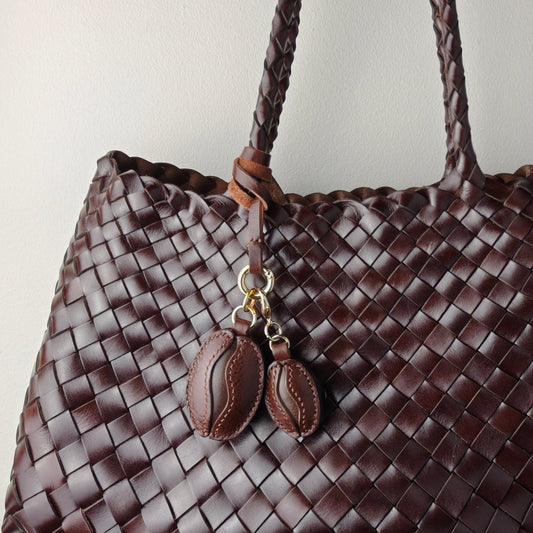 Handmade coffee bean charm made of premium full grain leather attached to a woven brown leather handbag