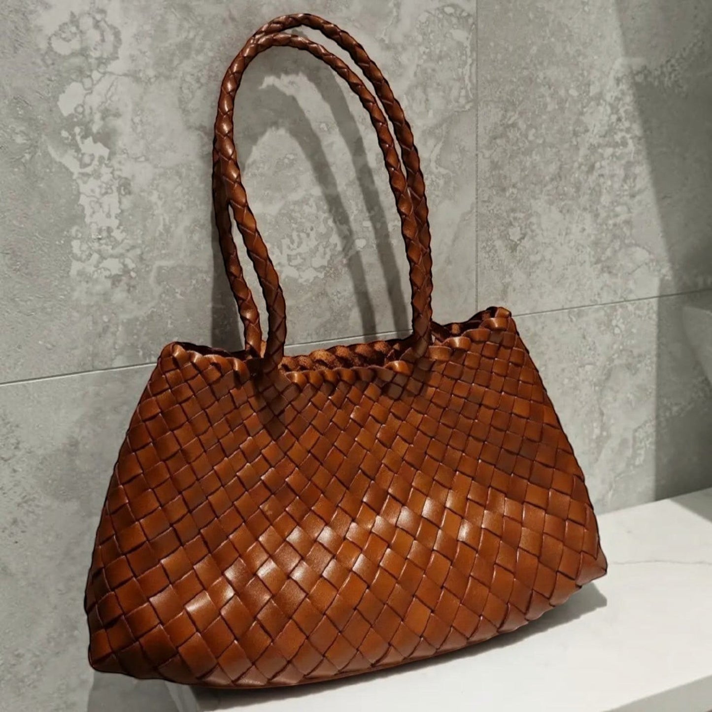 Brown woven handbag on a gray surface