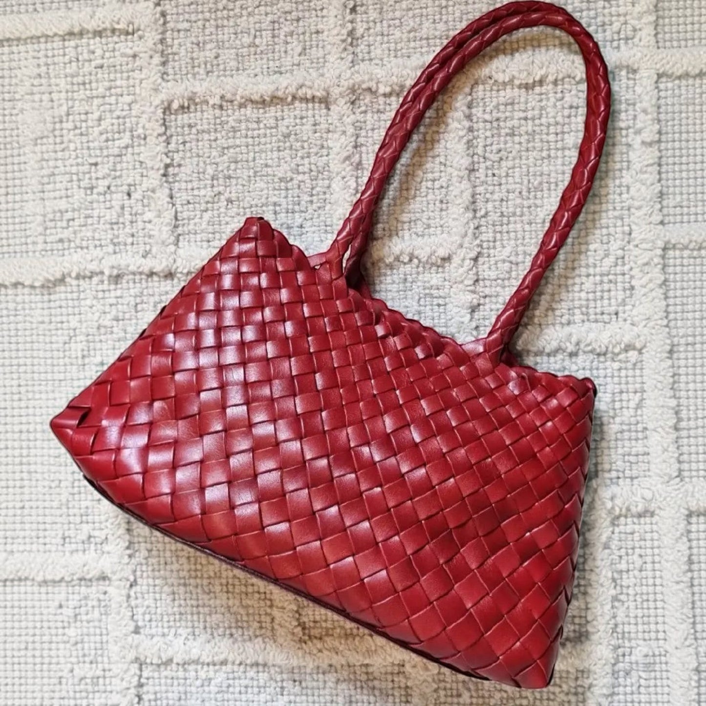 Red woven handbag on a textured beige surface