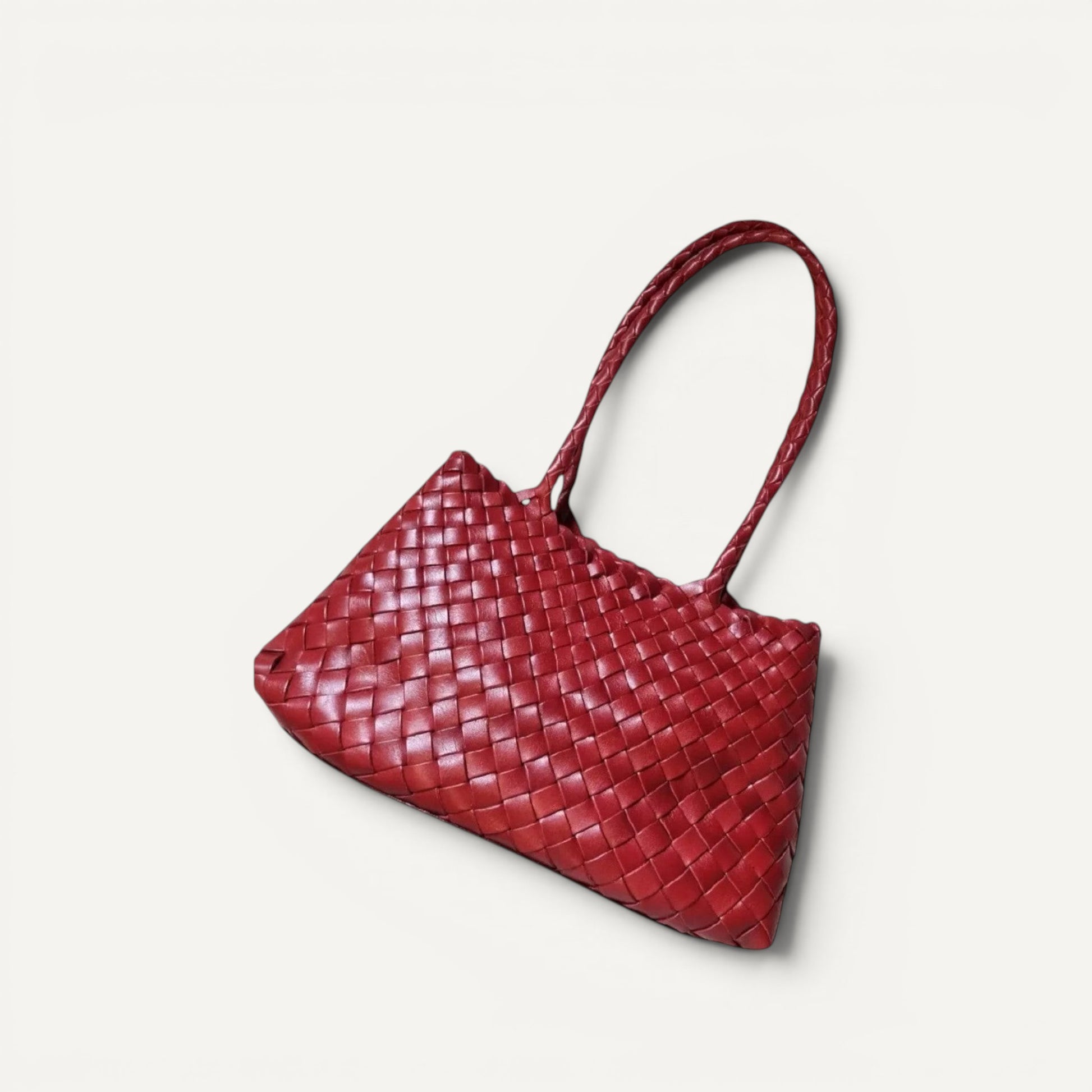 Red woven handbag on a textured beige surface