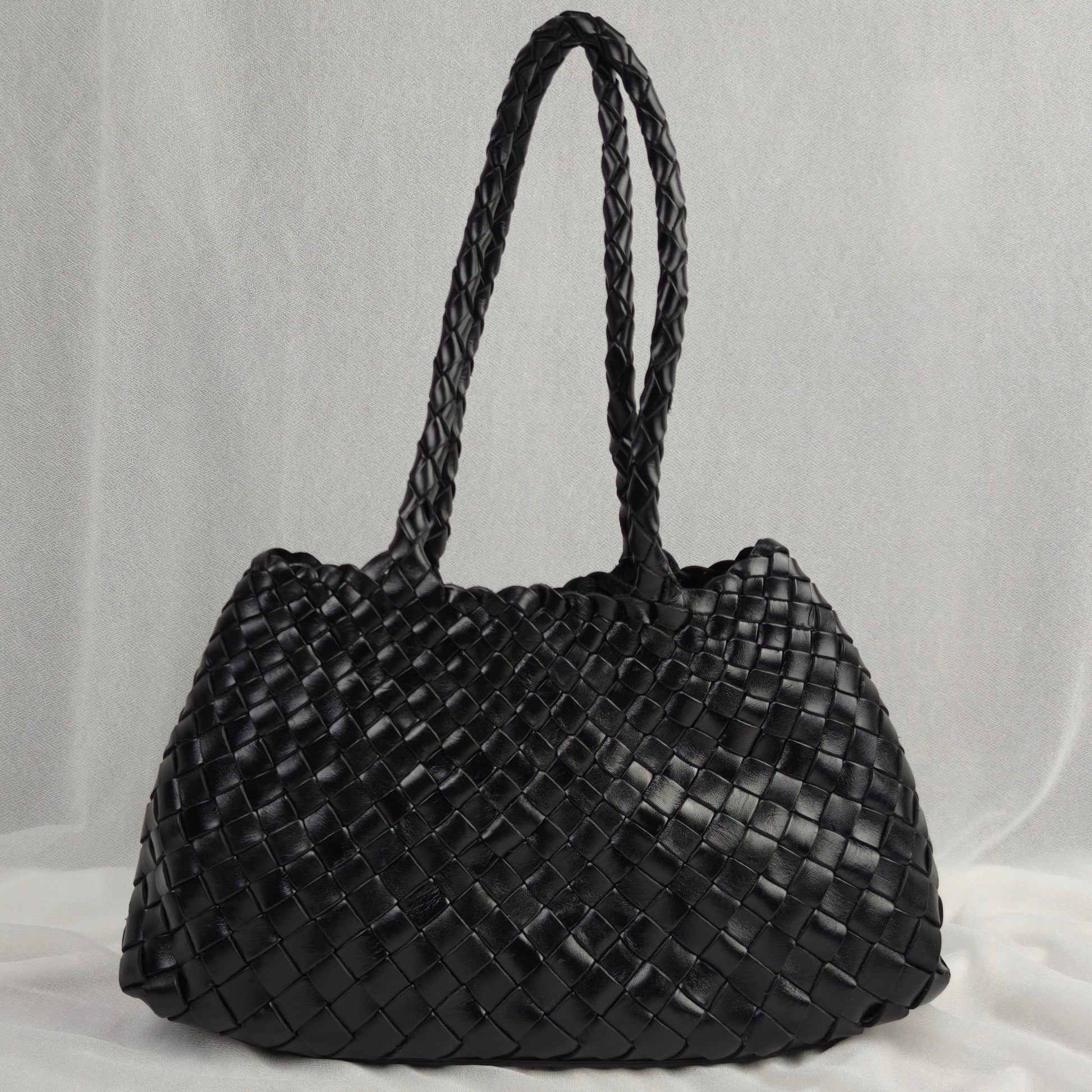 Black woven handbag on a light gray background