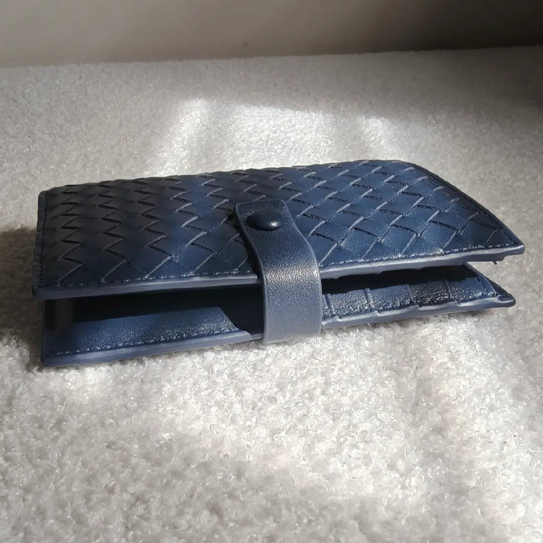 navy passport holder leather textured wallet side profile on a light gray surface