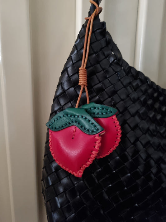 Peach charm accessory in multicolor faux leather on a handbag.