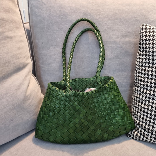 Handmade green cowhide leather woven shoulder tote bag with long handles on couch.