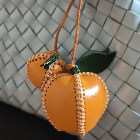 Apple Charm accessory on a woven handbag.