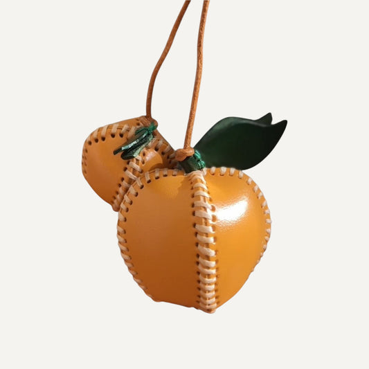 Apple Charm accessory on a woven handbag.